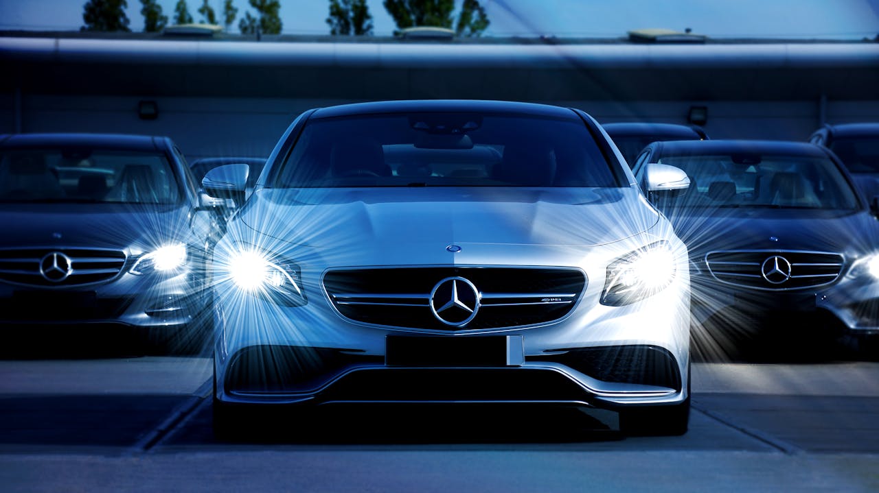 about-us Front view of a lineup of Mercedes-Benz cars with bright headlights, showcasing luxury and elegance.